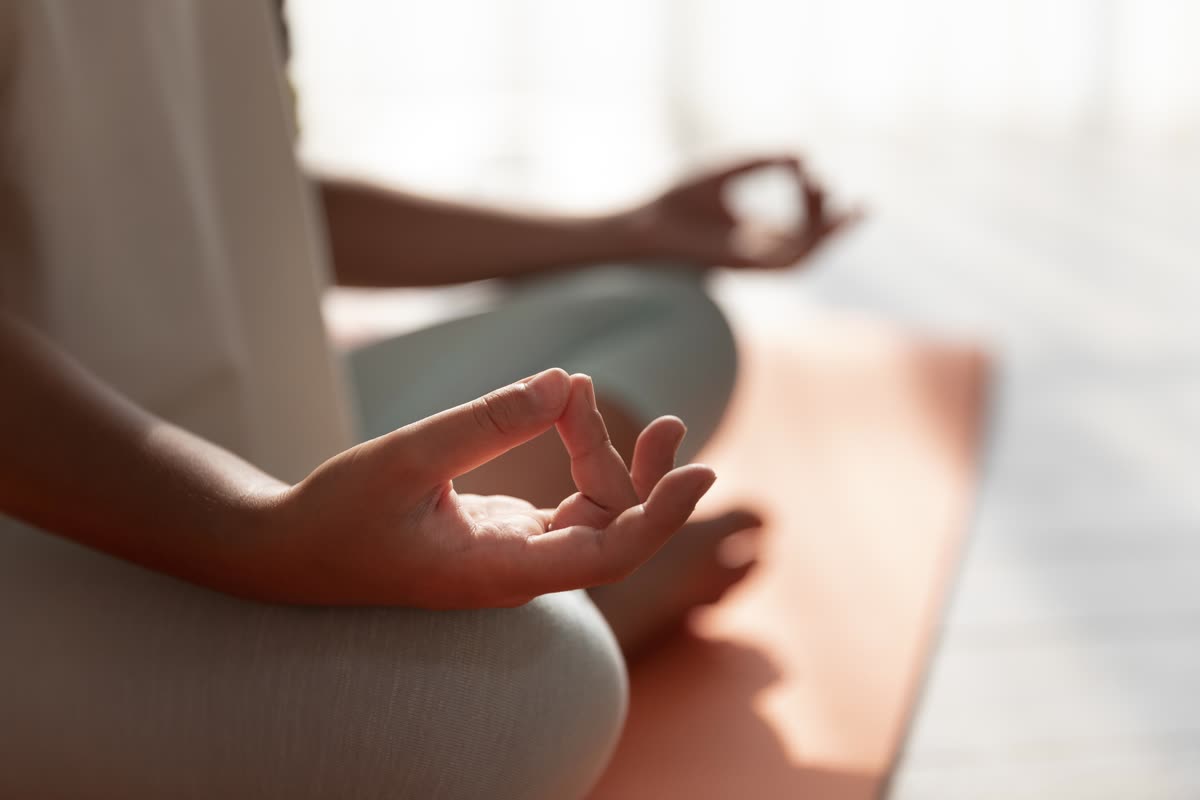 Hände in einer Mudra-Haltung beim Sitzen auf der Yogamatte